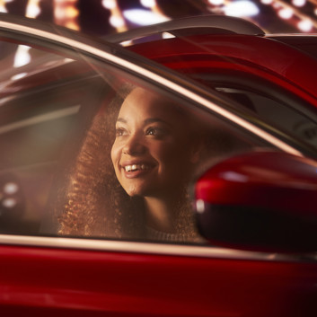 A woman smiling as she gets out of a car, at night