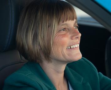 A woman smiling while driving a blue Motability Scheme car